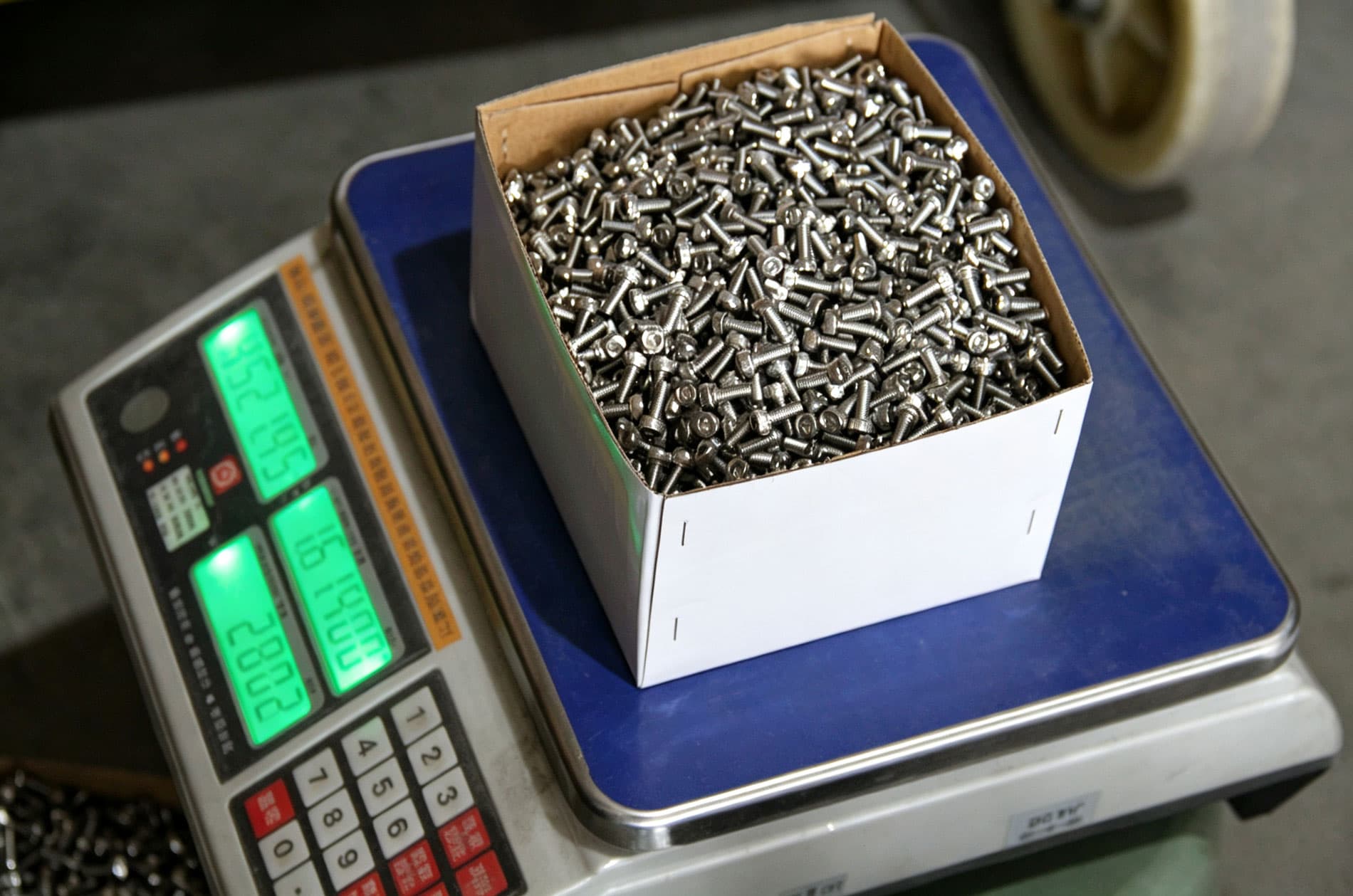 Box of stainless fasteners being counted on a digital scale